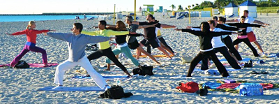 As these students hold their stance in Warrior Pose II, they are able to enjoy the beautiful view of the Atlantic Ocean (Photo courtesy of Third Street Beach Yoga).